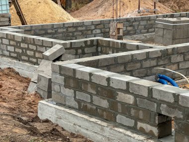 Çelik çubuklarla güçlendirilmiş beton zemindeki dört katmanlı beton bloklardan oluşan tek bir aile evinin temellerinin inşası.