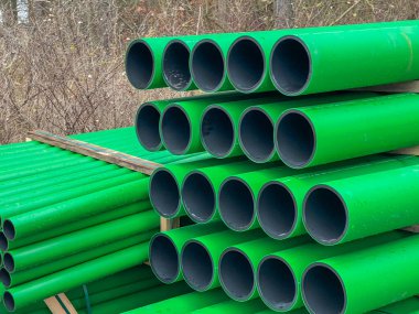 Kanalizasyon sahasında depolanmış arka plan olarak yan yana dizilmiş çubuklardaki yeşil kanalizasyon boruları.