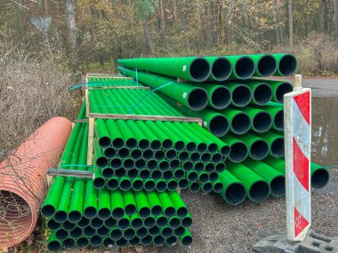 Kanalizasyon sahasında depolanmış arka plan olarak yan yana dizilmiş çubuklardaki yeşil kanalizasyon boruları.