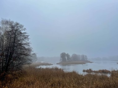 Göletin yüzeyinde, sonbaharın son günlerinde oluşan sis kasvetli ve iç karartıcı bir manzara yaratıyor..