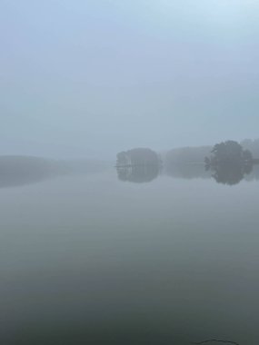 Fog over the surface of the pond occurring in the last days of autumn, creating a gloomy, depressing view but at the same time rarely seen. clipart