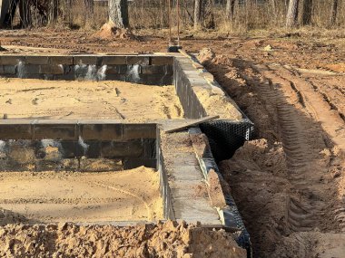 Tek bir aile evinin temellerini kumla kaplıyor ve temellerin içindeki alanı kumla dolduruyor..