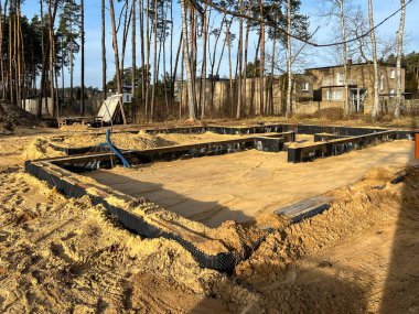 Tek bir aile evinin temellerini kumla kaplıyor ve temellerin içindeki alanı kumla dolduruyor..