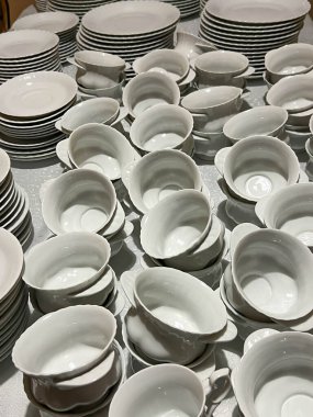 Bardaklar, tabaklar ve tabaklar masalara konmaya hazır beyaz ve gri renkli..