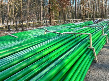 Kanalizasyon şebekesinin inşası sırasında yol kenarında depolanan yeşil ve kahverengi kanalizasyon boruları.