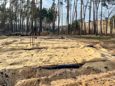 Tek bir aile evinin temellerini kumla kaplıyor ve temellerin içindeki alanı kumla dolduruyor..