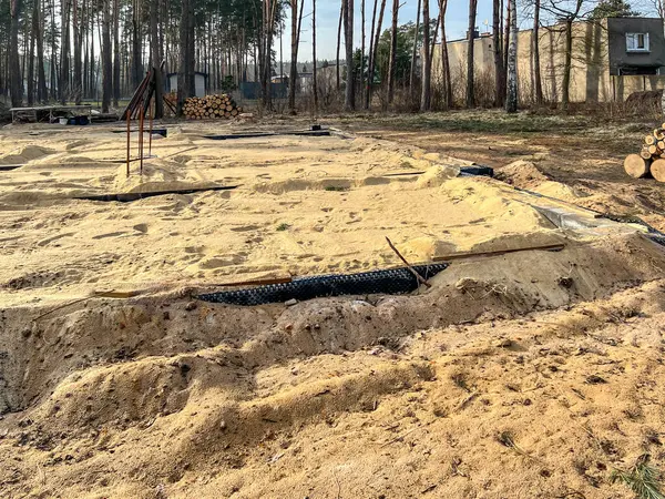 Tek bir aile evinin temellerini kumla kaplıyor ve temellerin içindeki alanı kumla dolduruyor..