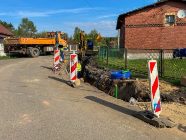 Kalety, Polonya, 24 Nisan 2025: Kırsal alanda bir kanalizasyon sistemi inşa edilmesi. Kırsala, yolun altına boru döşüyorlar..