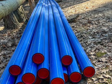 Ormanın otoparkında saklanan kırmızı başlıklı mavi plastik borular yere gömülmeye hazır..