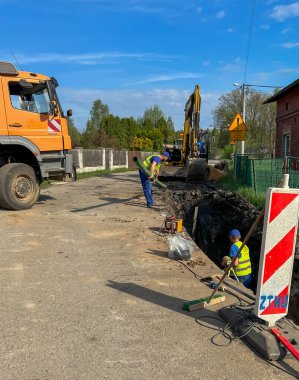 Kalety, Polonya, 24 Nisan 2025: Kırsal alanda bir kanalizasyon sistemi inşa edilmesi. Kırsala, yolun altına boru döşüyorlar..