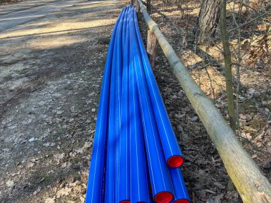 Ormanın otoparkında saklanan kırmızı başlıklı mavi plastik borular yere gömülmeye hazır..