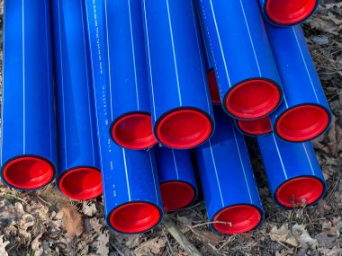 Ormanın otoparkında saklanan kırmızı başlıklı mavi plastik borular yere gömülmeye hazır..