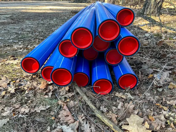 Ormanın otoparkında saklanan kırmızı başlıklı mavi plastik borular yere gömülmeye hazır..
