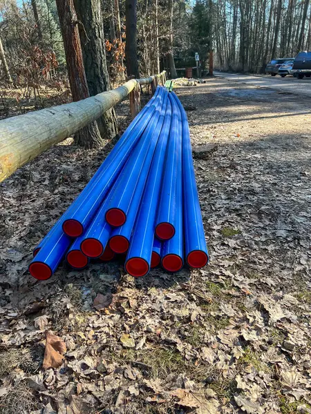 Bir orman otoparkında depolanmış mavi plastik borular kanalizasyon sisteminin inşası ve su kaynaklarının modernizasyonu sırasında yerin altına gömülmeye hazır..
