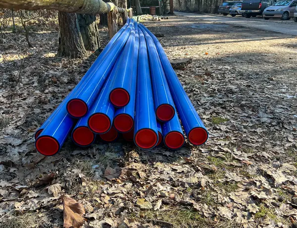 Bir orman otoparkında depolanmış mavi plastik borular kanalizasyon sisteminin inşası ve su kaynaklarının modernizasyonu sırasında yerin altına gömülmeye hazır..