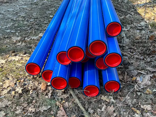 Ormanın otoparkında saklanan kırmızı başlıklı mavi plastik borular yere gömülmeye hazır..