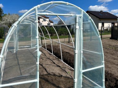 Sebzelerin olgunlaşmasını hızlandırmak için bir bahçe içine folyo tüneli yerleştirmek..