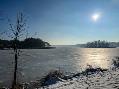 Kar ve buzla kaplı bir göletin üzerinde kış güneşi.