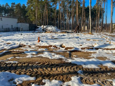Kışın ağaçların arasında, karla kaplı tamamlanmış tek bir aile inşaat sahası..