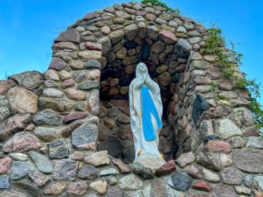 Meryem 'in mağaradaki figürü (Fransa' nın Lourdes şehrindeki gibi) Rokitno 'daki Küçük Meryem Ana Bazilikası' nın bahçesinde sabırla dinlerken.