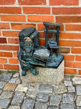 Wroclaw, Polonya, 22 Temmuz 2025: Wroclaw, Polonya 'daki Ostrow Tumski Adası' ndaki Yazıcı Cüce Casper. Cüceler - küçük heykelcikler, Wroclaw 'da turistik bir cazibe.