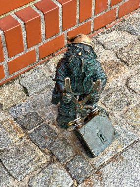 Wroclaw, Polonya, 22 Temmuz 2025: Wroclaw, Polonya 'daki Oder Nehri yakınlarındaki Piasek Adası' nda asma kilit kesen bir cüce. Cüceler - küçük heykelcikler, Wroclaw 'da turistik bir cazibe.