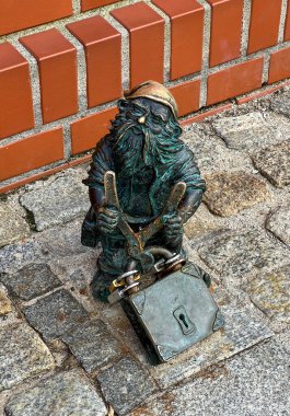 Wroclaw, Polonya, 22 Temmuz 2025: Wroclaw, Polonya 'daki Oder Nehri yakınlarındaki Piasek Adası' nda asma kilit kesen bir cüce. Cüceler - küçük heykelcikler, Wroclaw 'da turistik bir cazibe.