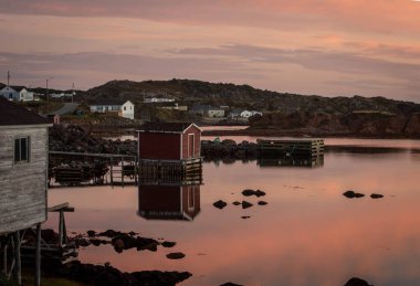 Red fishing shack reflects on the water in Twillingate Newfoundland 