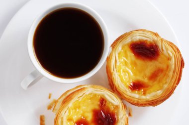 Tipik Portekiz pastel de nata yumurtalı turtası. Beyaz arka planda bir fincan kahve, üst manzara.