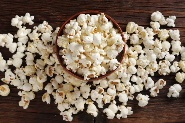 Popcorn in a bowl on wooden background, top view. Cinema snack concept