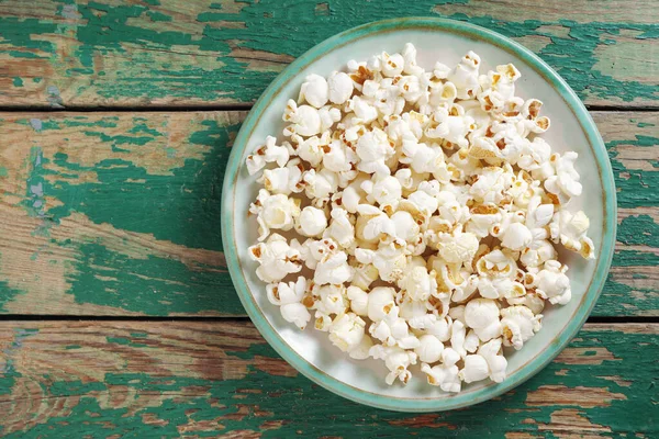 stock image Popcorn in a plate on old green wooden background, top view with copy space 