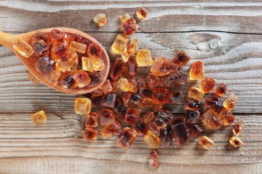 Tahta arka planda kaşık içinde büyük karamelize şeker, üst görünüm.