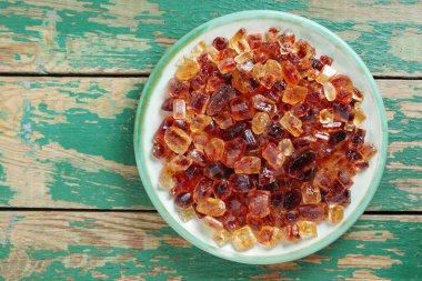 Büyük kahverengi kaya şekeri kristalleri eski yeşil ahşap masa üzerinde, fotokopi alanı ile üst manzara