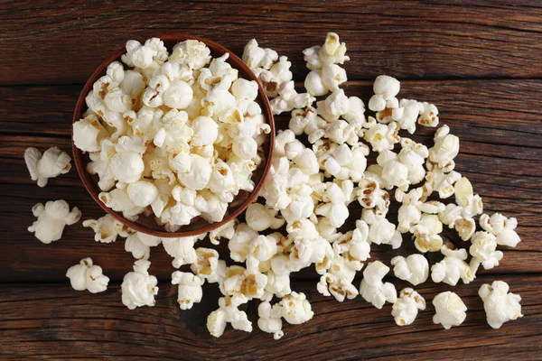 Popcorn in a bowl on wooden background, top view