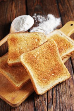 Ahşap masada, mutfak tahtasının üzerinde kızarmış ekmek dilimleri. Yaklaş.