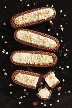 Krema aromalı bisküviler siyah metal tepsi arka planında kırılmış ve bütün olarak duruyor.