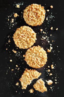 Biscuits with peanuts whole and broken on a black metal tray background, top view