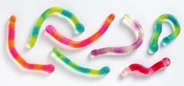 Colorful gummy jelly worm candies on white background, top view