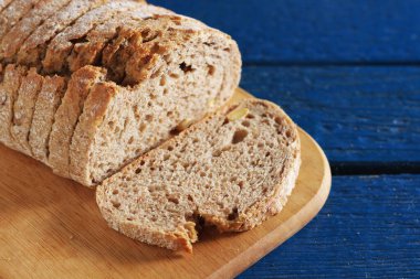 Mavi ahşap masada tahtayı kesen tohumlu ekmek dilimleri