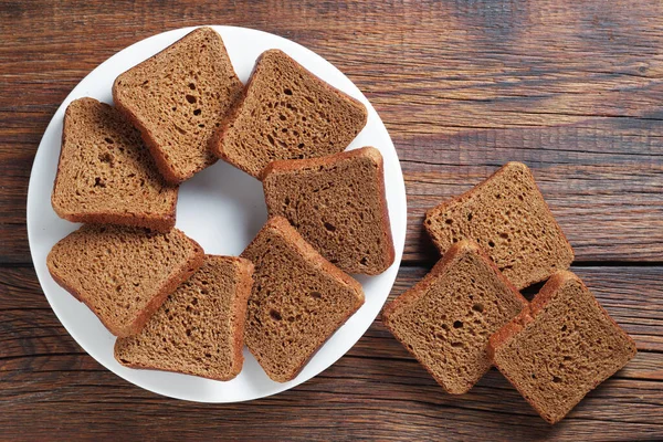 木製の背景に皿の上に小さなライ麦パンのスライス トップビュー — ストック写真