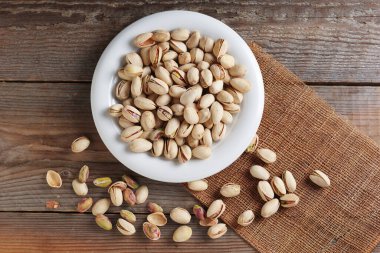 Ahşap arka planda bir çanakta fıstıklar, üst manzara.