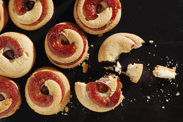 Shortbread cookies with jam on a black tray background, top view