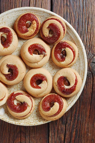 stock image Biscuits cookies with jam on a plate on wooden background, top view 