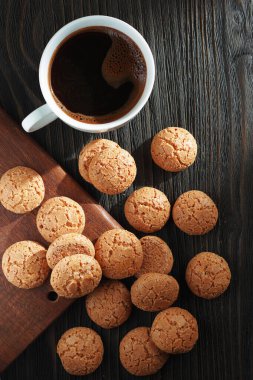 Kayısı kaplı İtalyan bisküvileri ve eski siyah ahşap arka planda bir fincan kahve.