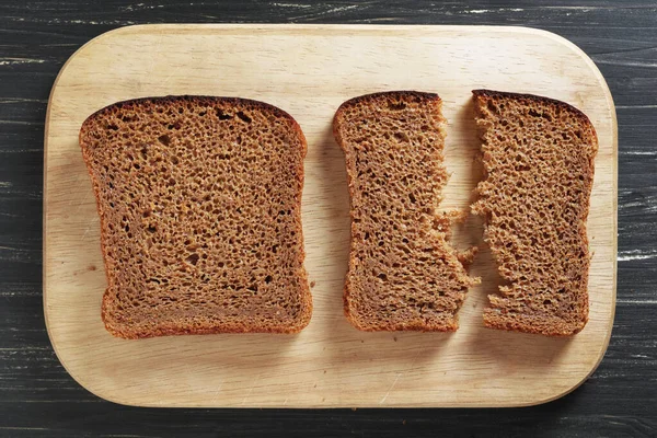 黑色切片面包与木制背景的切菜板对比 顶部视图 — 图库照片