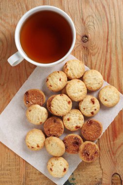 Eski ahşap arka planda reçelli kurabiyeler ve bir fincan çay.
