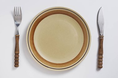 Beyaz zemin üzerinde çatal ve bıçak olan boş tabak, üst görünüm