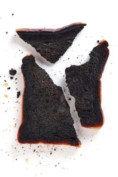 Pieces of burnt toasted bread on white background, top view