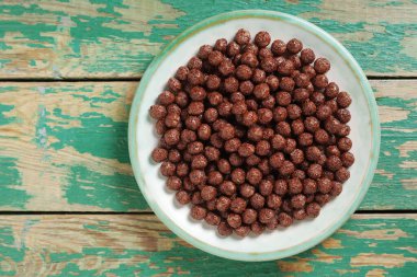 Eski yeşil ahşap arka planda bir tabakta çikolatalı mısır topları, fotokopi alanı olan üst manzara.