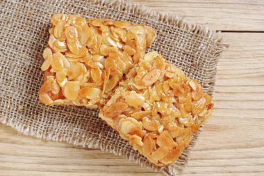 Ev yapımı ballı pasta, badem ve çuval bezi, ahşap masa, üst manzara.